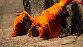 Buddhist Monks climbing up the temple in Siem Reap, Cambodia